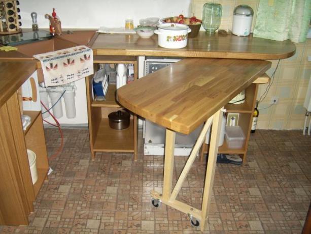 Na foto - uma mesa dobrável em uma pequena cozinha