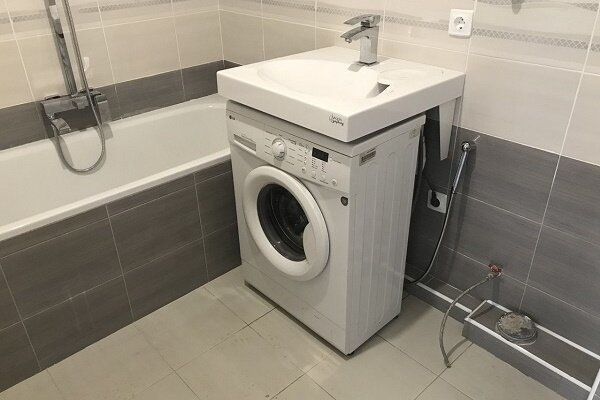 Máquina de lavar roupa sob a pia no banheiro