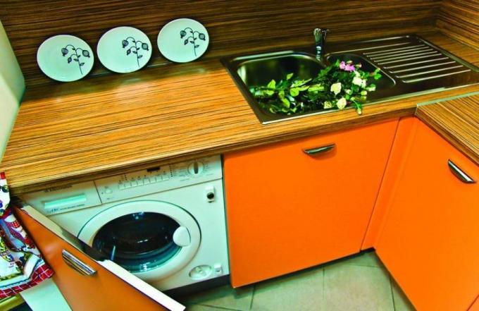 Máquina de lavar roupa na cozinha sob a bancada