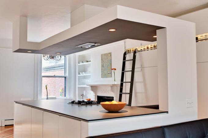 As transições de placa de gesso, como na foto, são frequentemente usadas para aprimorar o zoneamento em cozinhas combinadas com outras salas